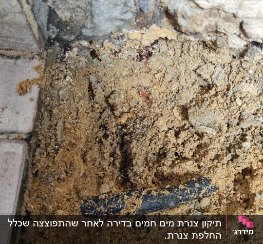 צינור שחור שבור בתוך אדמה וחול